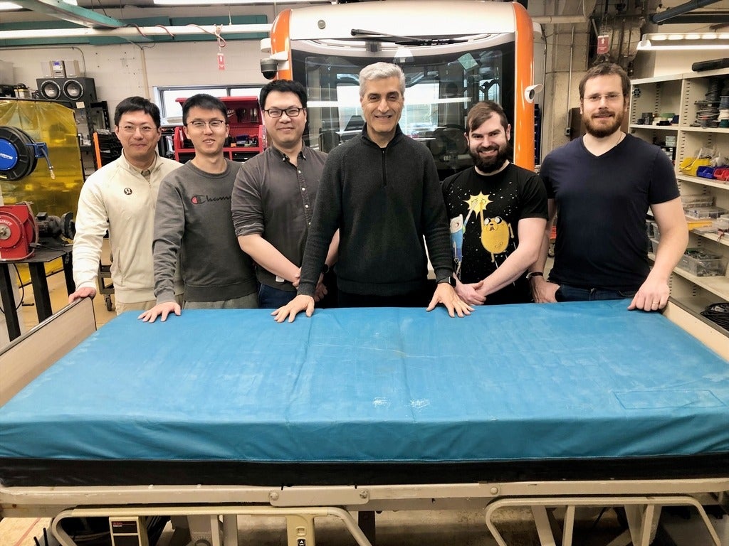 Researchers pose with a robotic bed they are using to develop an autonomous mobility system for hospitals.
