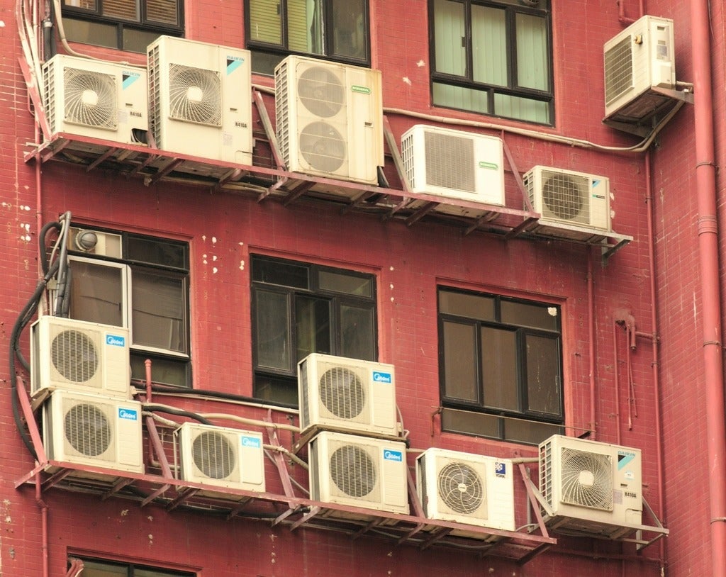 Multiple building cooling fans on the outside of a red building