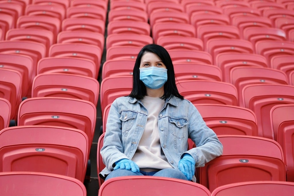 Woman in mask sitting in bleachers