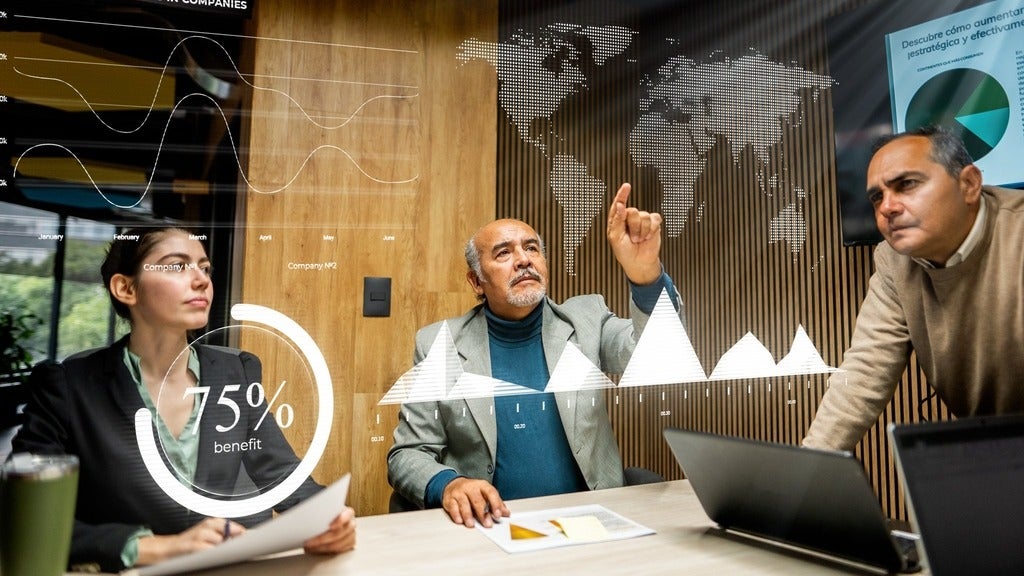 Team of executive leaders pointing at a hologram of the world map 