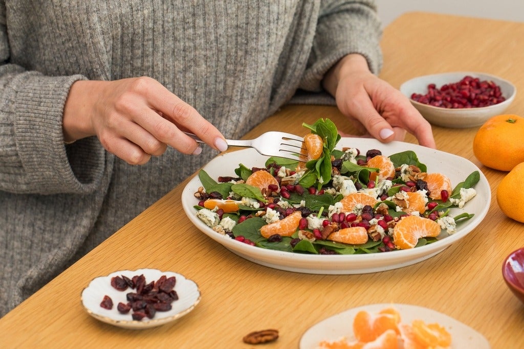 A person eating a winter salad with fresh spinach, mandarin and pomegranate (Getty Images/Victoria Popova).