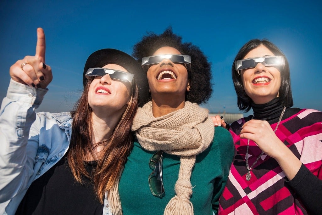 Group of friends looking to a solar eclipse wearing solar eclipse glasses.