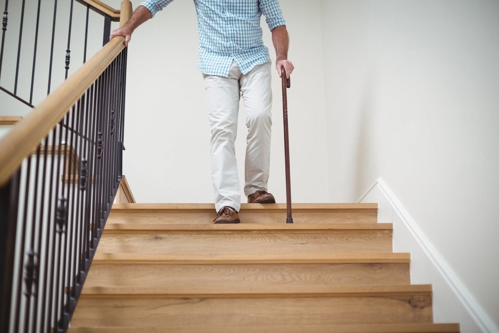 Senior man climbing downstairs with walking stick 