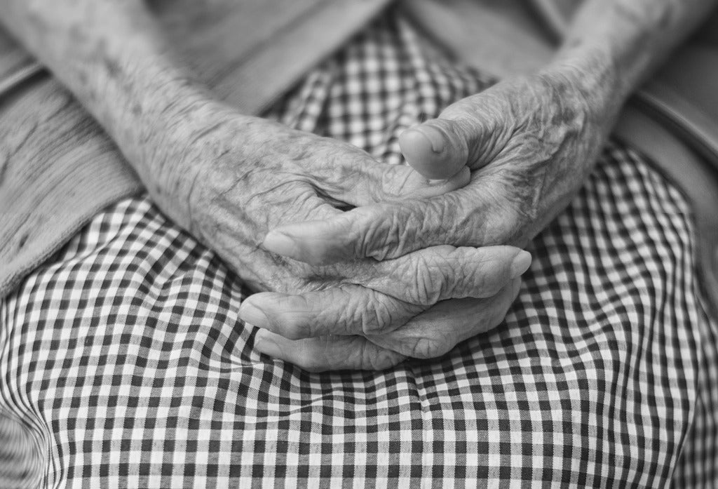 Clasped hands resting on lap