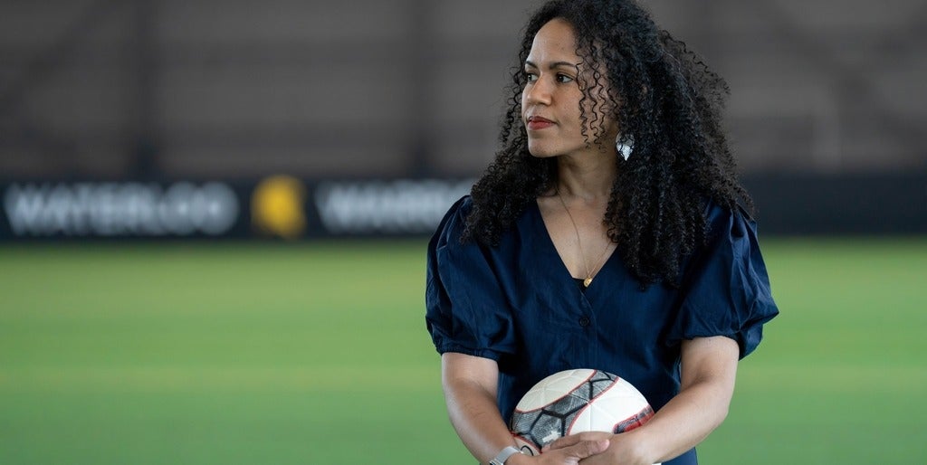 Dr. Kaleigh Pennock stands inside the field house holding a soccer ball