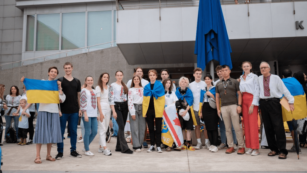 A group of students and adults pose in front of City Hall with Ukrainian flags