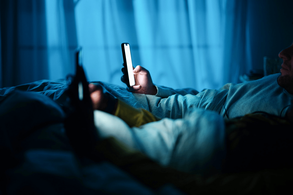 couple using their phones in a dark bedroom