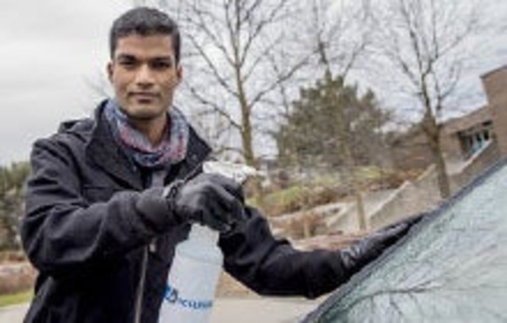 Abhinay Kondamreddy sprays Neverfrost on a windshield