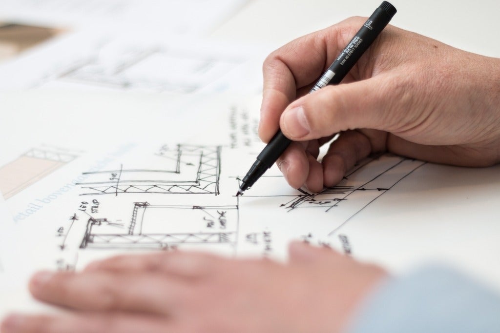 person holding a black pen and designing on paper