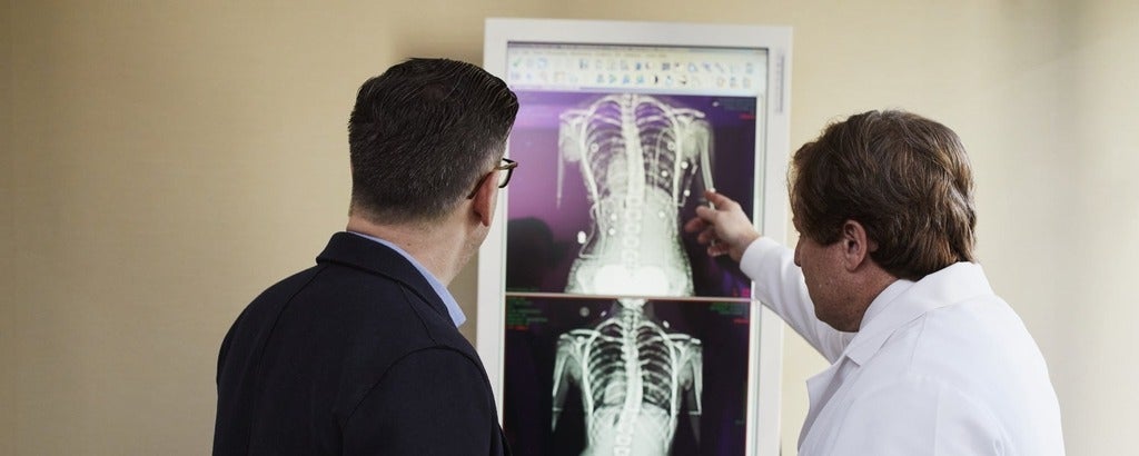 Doctor pointing to x-ray results to man wearing black suit
