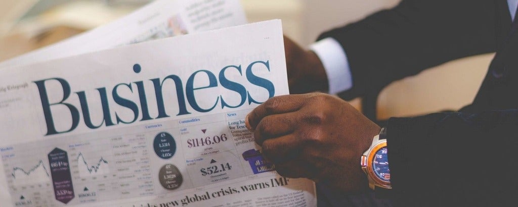 Man holding Newspaper with business in the front 
