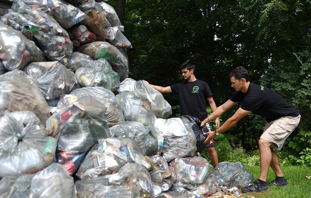 Pickwaste founders next to garbage bags