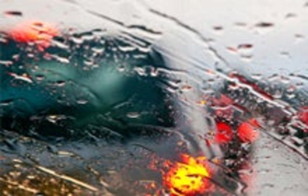 Blurry view through a rain streaked car windshield.