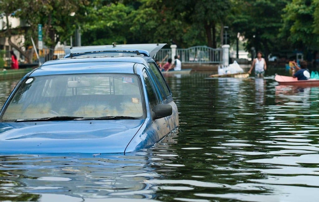 Sinking car with people on boats in background
