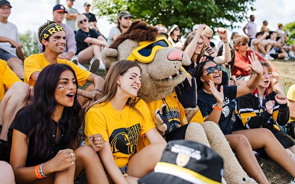 King Warrior sits with students at Black and Gold Day