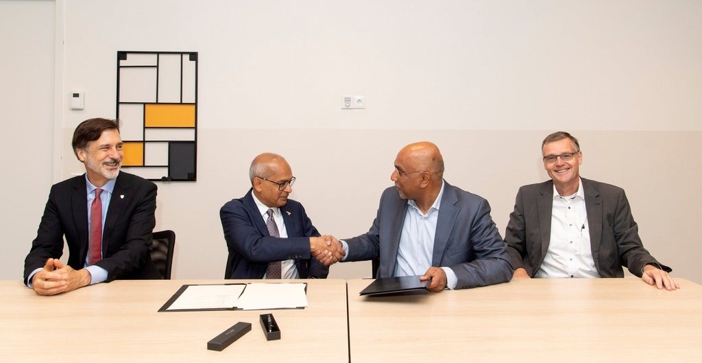 Vivek Goel shakes hands with the President of the universiteit ondertekening.