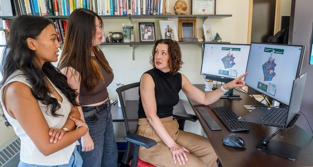 Leia Minaker points out something on a computer screen to Faculty of Environment students Miki Zheng and Alexa Rigonan