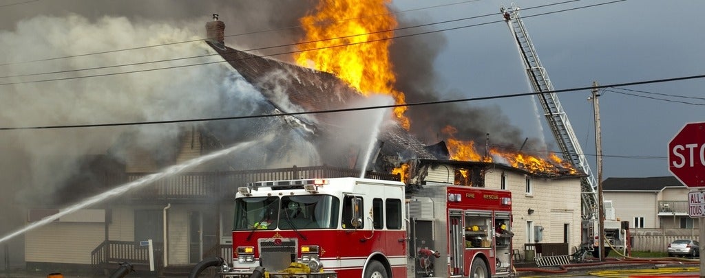 Fire fighters responding to fire in a large building engulfed in flames
