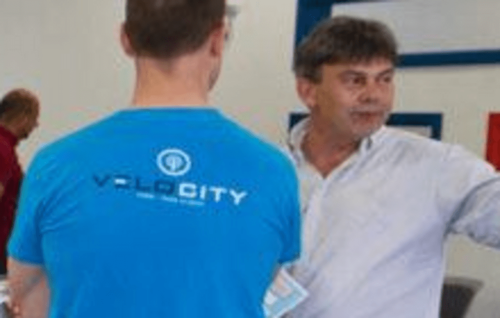 Student in Velocity shirt speaking to an open house attendee