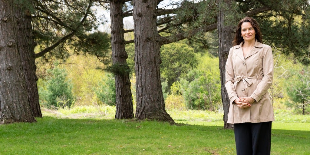 Anabela Bonada stands amongst trees on a partly cloudy day