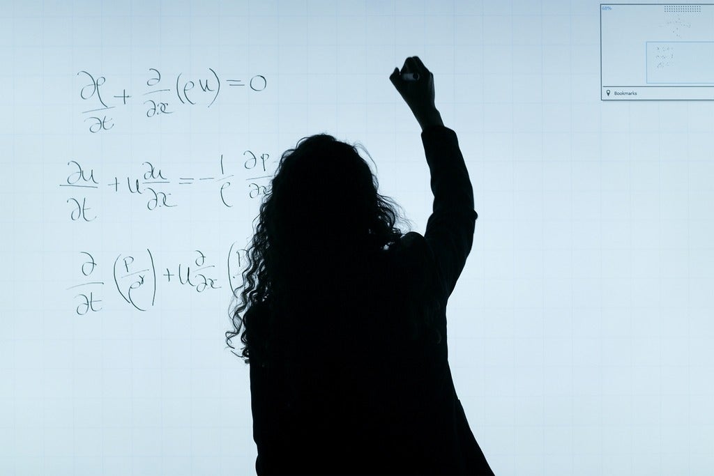 Silhouette of a woman, writing equations on a white background 