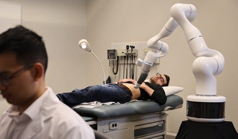 Patient is treated by CODI robotic arm with practitioner in foreground
