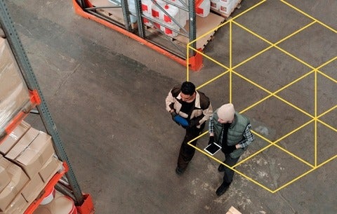 Two people working with a tablet in a warehouse