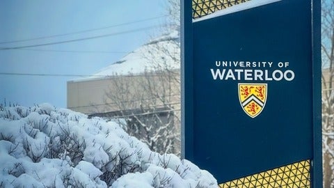 University of Waterloo signage behind a tree full of snow