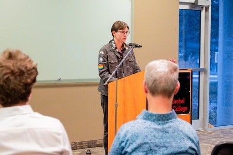 Lucas Shumaker speaking from a podium at Conrad Grebel University College