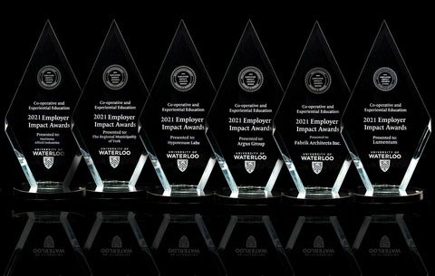 six glass awards lined up on a black table