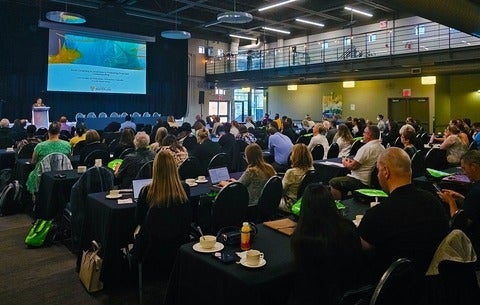 Room full of conference attendees seated at tables at Federation Hall