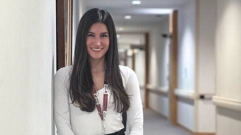 Jackie Diabold leans against a wall while smiling at the camera