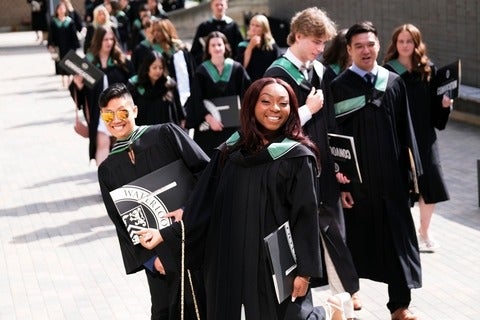 A group of Class of 2024 students jump in the air outside convocation hall