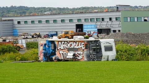 Old bus with graffiti paintings resting on a green lawn