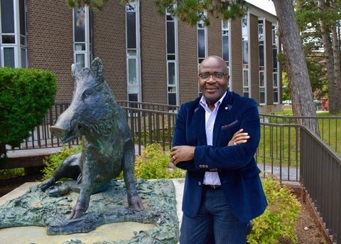Dr Alexie Tcheuyap with sculpture of boar on campus