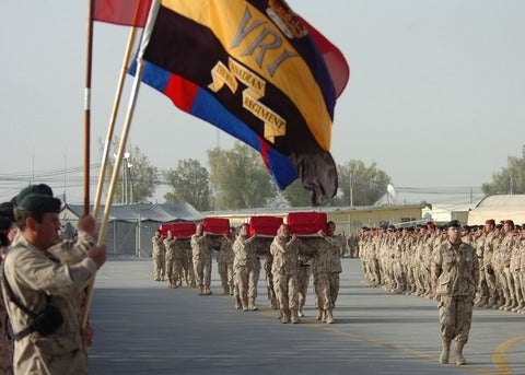 Rows of soldiers standing by while caskets pass by