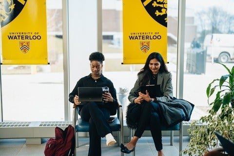 Two University of Waterloo student women sitting in the Tatham Centre lobby waiting for their interviews