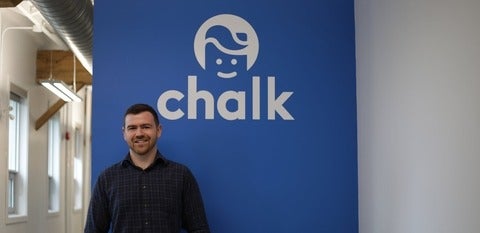 Kynan Gallagher in front of his company logo
