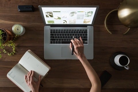 hands working at a desk and laptop