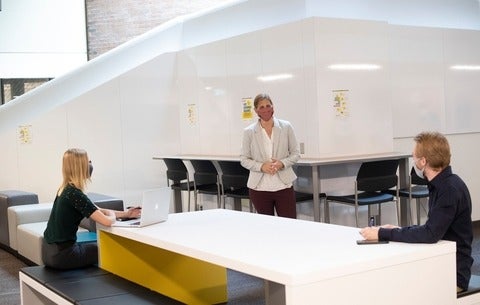 Three students gathered around a table in professional attire