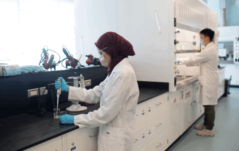 Two people wearing masks, working in a lab