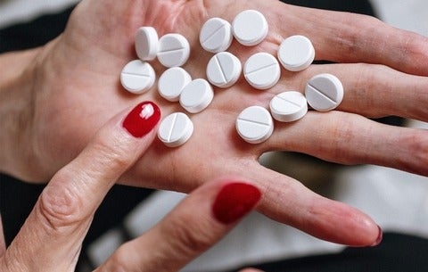 Woman holding white tablets in her hand