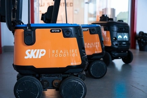 3 orange wheeled robotic boxes with logos for Skip and Real Life Robotics on their sides