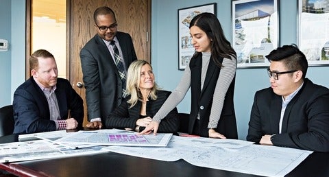 Debra Kakaria standing at a table with colleagues
