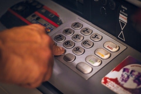 Hand pressing buttons on a bank machine to withdraw cash