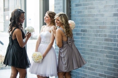 Bride holding white flowers and two bridesmaids smiling with her