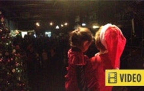Woman in Santa hat holding young child - article contains video
