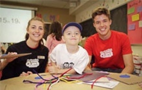 student works on a camp activity with leaders