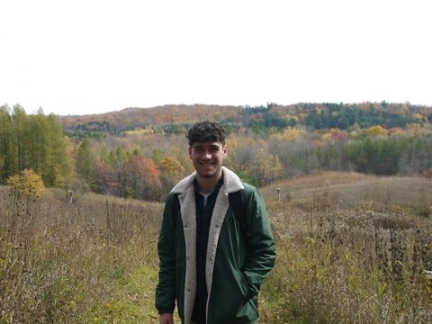 Ethan stands in a meadow in autumn