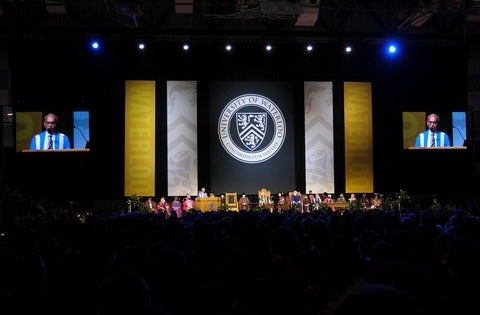Convocation stage features Vivek Goel at podium and dignitaries seated with the Waterloo crest on a banner behind the stage.